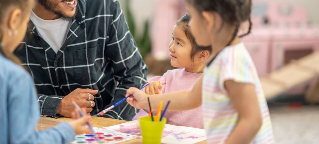 enfants dans une garderie à une table en train de faire de la peinture