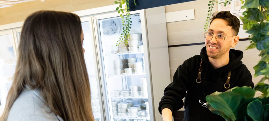 Un homme de chez FoodChéri derrière un comptoir lors de la pause déjeuner. 
