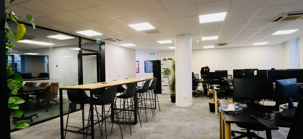 open space de bureaux avec tables hautes, chaises et également des bureaux avec ordinateurs