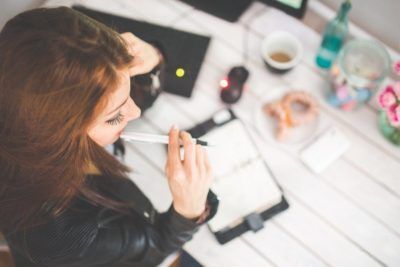 Femme assise en train de réfléchir sur son carnet