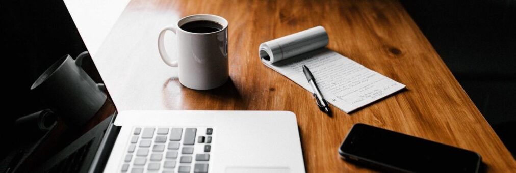 Bureaux avec ordinateur, tasse de café, bloc note et stylo et téléphone portable posés