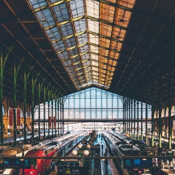 Intérieur de la gare du nord avec des trains à quais et verrières et poutres apparentes