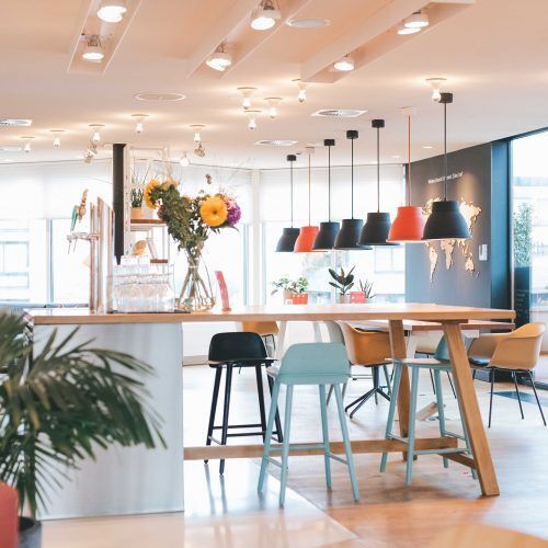 Table haute avec chaise et lampes colorées dans un open-space aux couleurs claires
